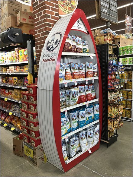 A boat shaped display for potato chips which includes the cape cod potato chips logo of a lighthouse on the ocean.