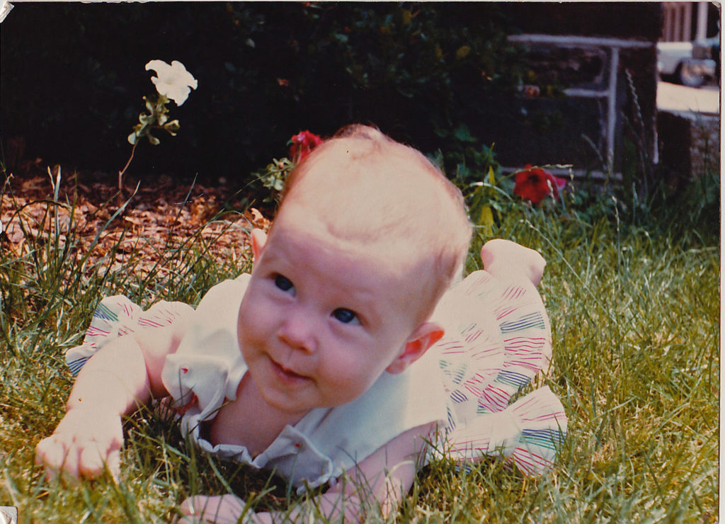 A photo of a caucasian baby in the grass