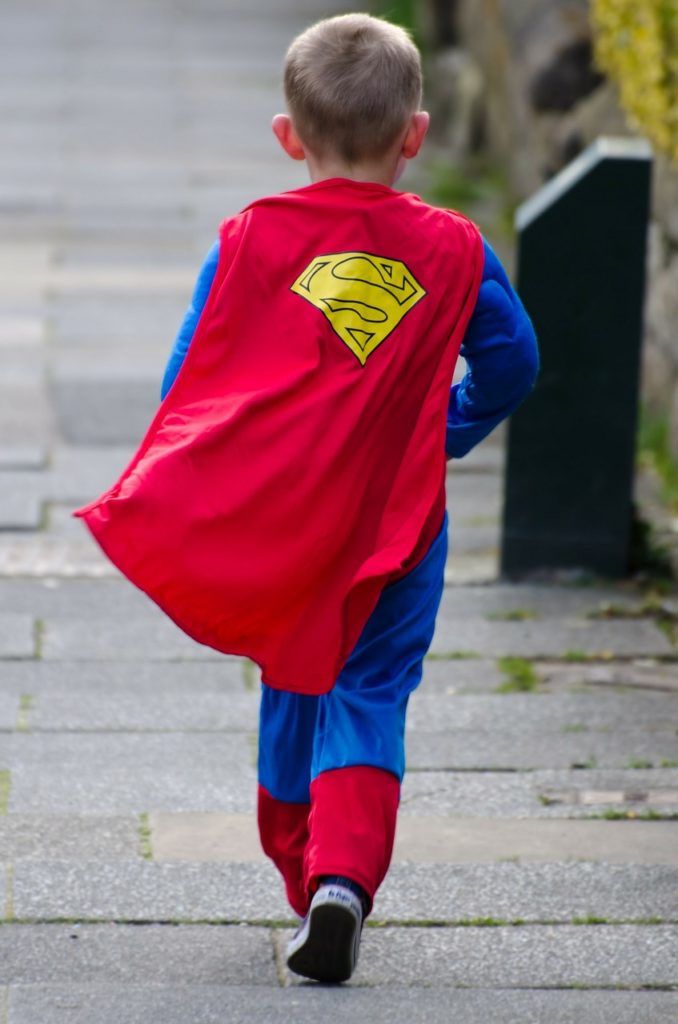 An image of a child from behind. The child is wearing a superhero costume.