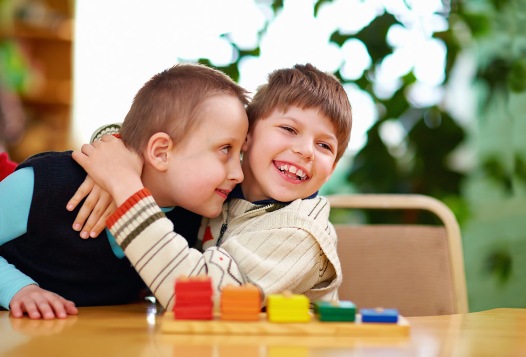 An image of two male preschool children hugging.