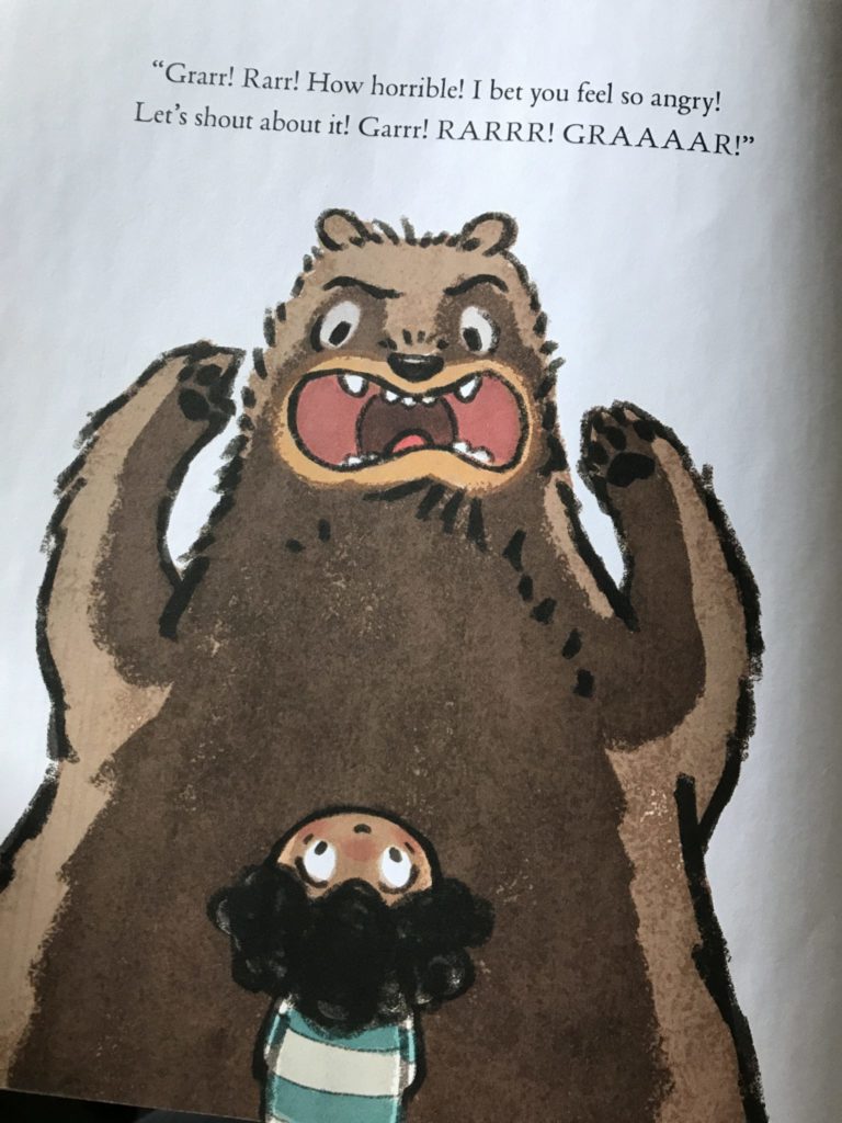 A picture of a bear with his mouth open, roaring.  A small child is looking up at the bear with his eyes open and head tipped back.