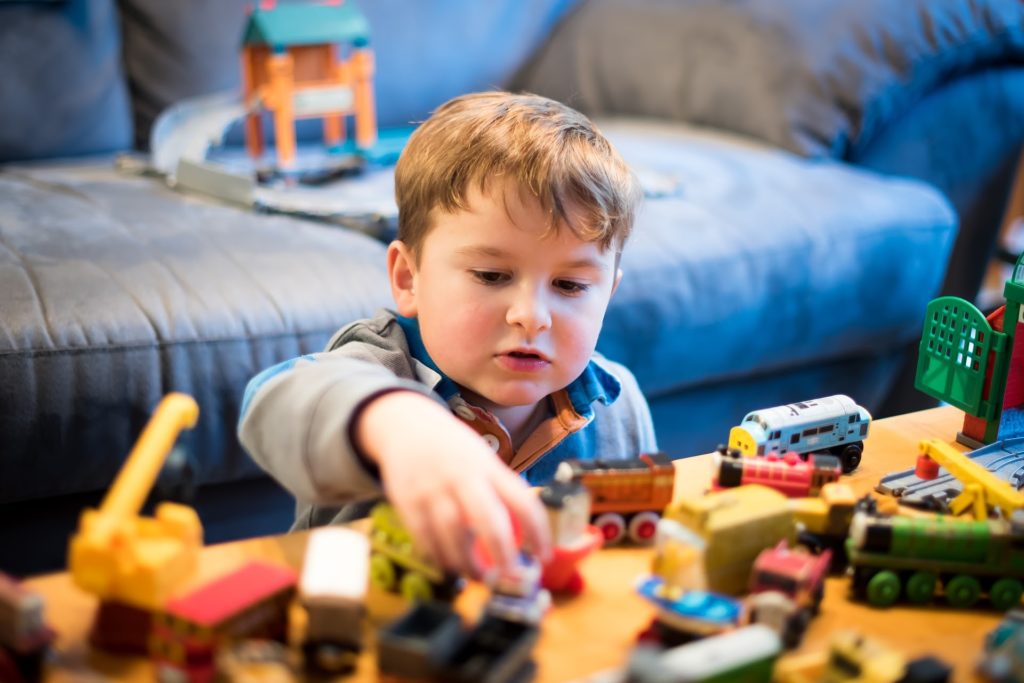 An image of a preschooler playing with trains on a table.