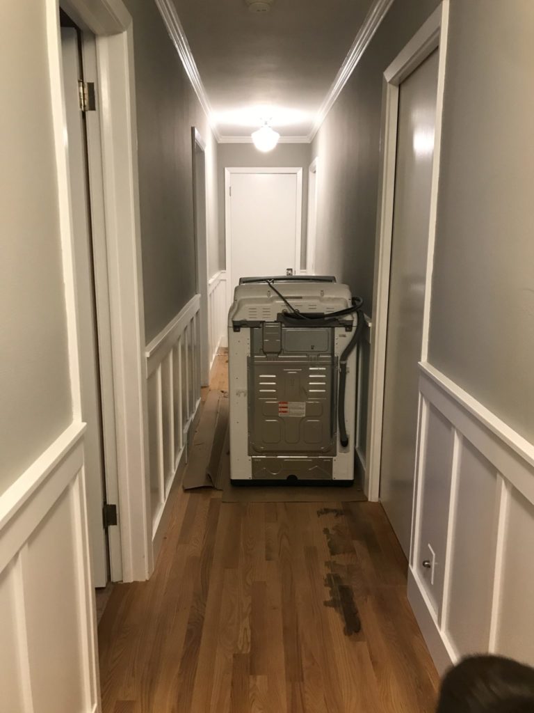 A long hallway with a washing machine in the middle of it. 