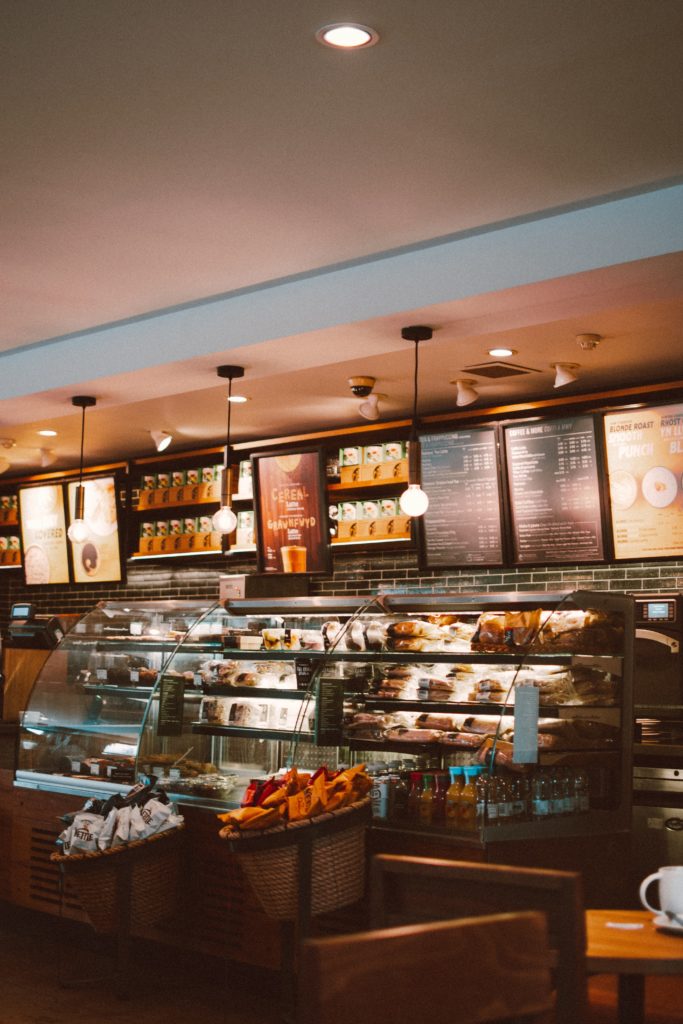 An image of the inside of a coffee shop counter, with food and menu boards visible