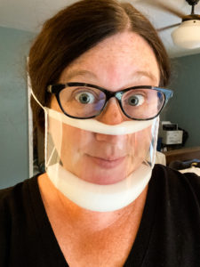 An image of Bridget's face and neck, with a clear face mask covering her mouth and nose. 