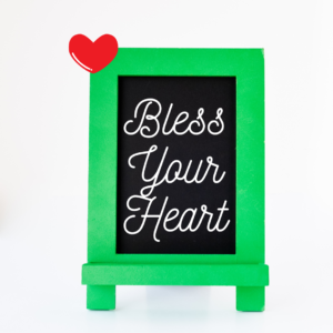 A green chalkboard with white lettering contains the figurative language phrase "Bless your heart" with a red heart