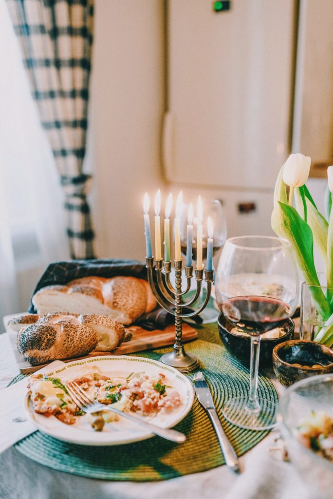 A table with a Mennorah and plates with leftover food. A loaf of bread is visible and a glass of wine.